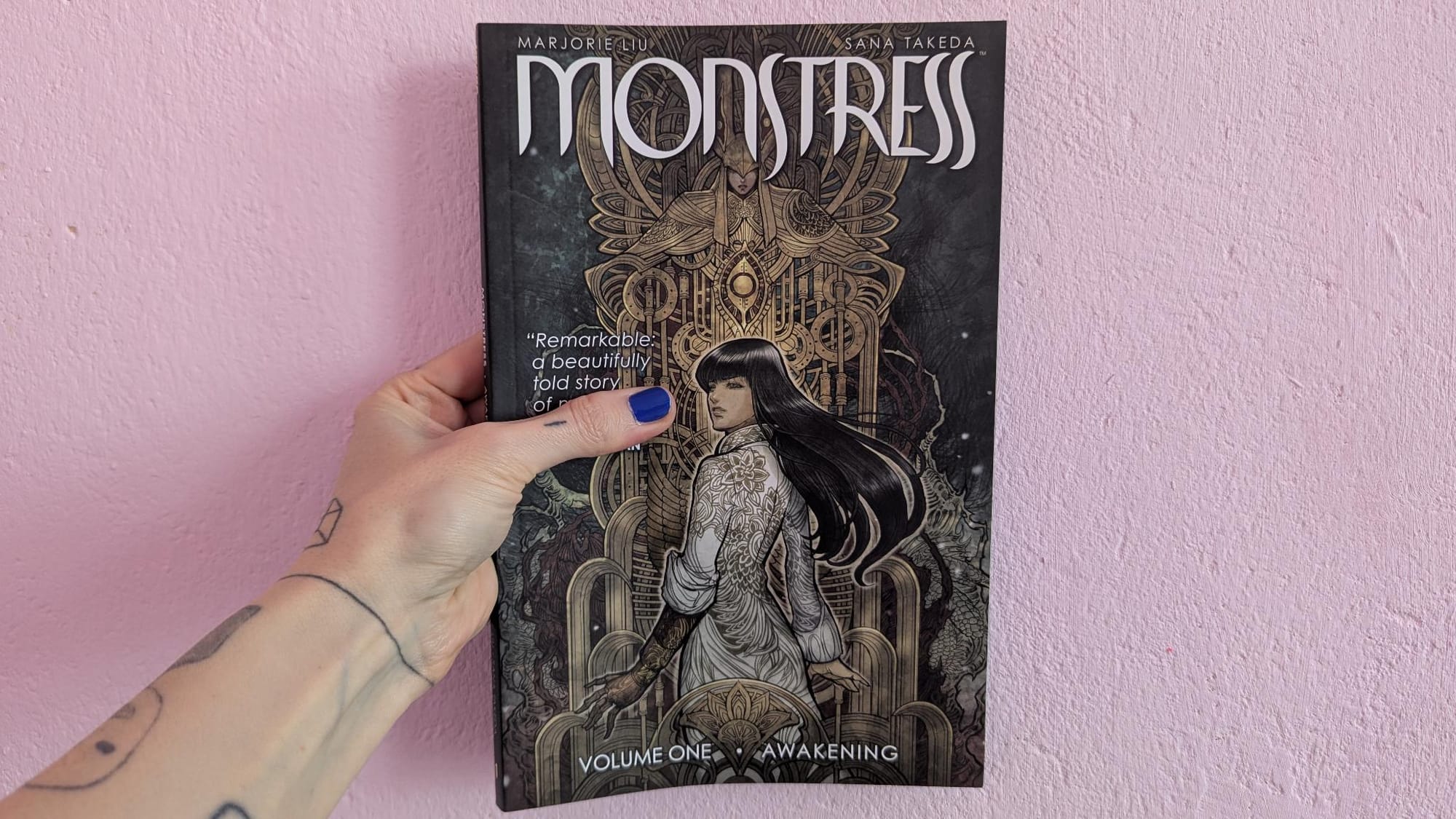 paperback copy of "monstress" by marjorie lui & sana takeda featuring very intricate hand-drawn art
